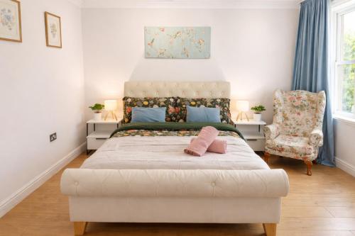 a bedroom with a large white bed and a chair at Spacious Double Room in Shared Flat in Sutton