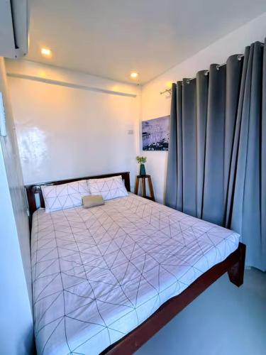 a bedroom with a bed in a room with curtains at DJL Beach House - Bantayan Island in Patao