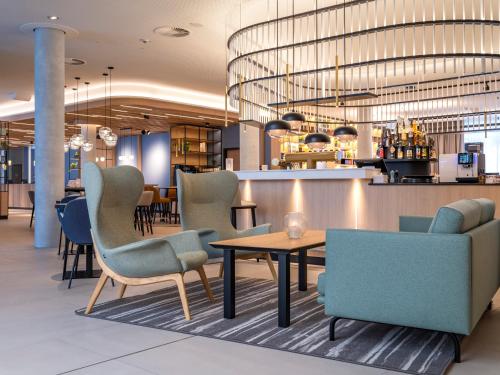 a lobby with chairs and a table and a bar at ScanHotels Stadthafen in Rostock