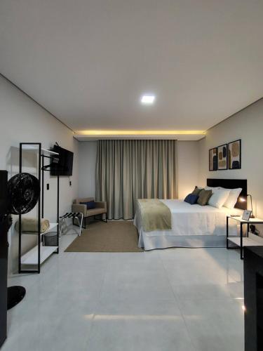 a large bedroom with a bed and a television at Studios Leme 11 - conforto para casal - com varanda in Espirito Santo Do Pinhal