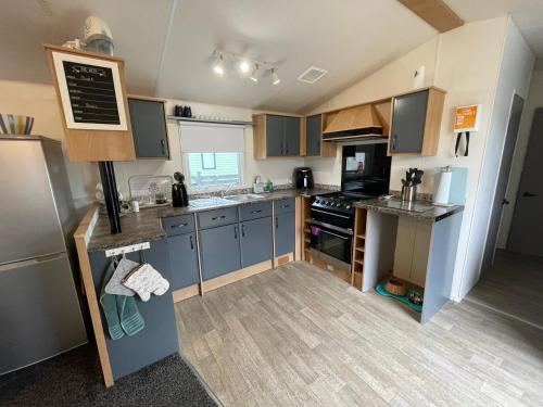 a small kitchen with blue cabinets and a counter top at 6 Rannoch, lovely holiday static caravan for dogs & their owners. in Forfar