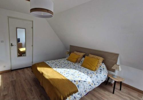 a bedroom with a bed with yellow pillows on it at Chambre confortable chez Isabelle in Cléden-Cap-Sizun