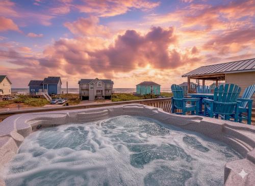a hot tub on a deck with chairs and a table at On The Beach - Kitty Hawk, MP 1, Less than 50 Yards to Beach, Ocean View, Pool, Hot Tub, Pets OK in Kitty Hawk
