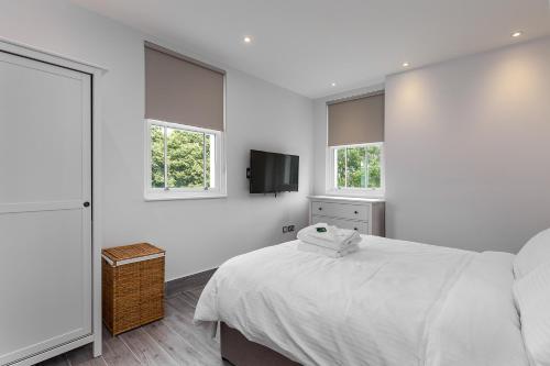 a white bedroom with a bed and a flat screen tv at The Lion Gate Mews in Kingston upon Thames