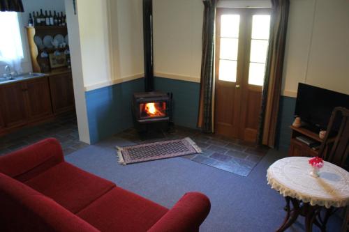 a living room with a red couch and a fireplace at Coonawarra's Pyrus Cottage in Coonawarra