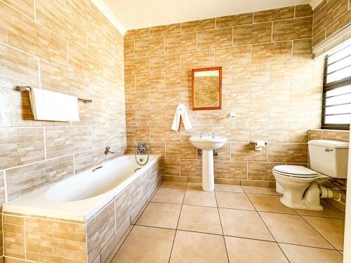 a bathroom with a tub and a toilet and a sink at Fluisterbaai in Britannia Bay