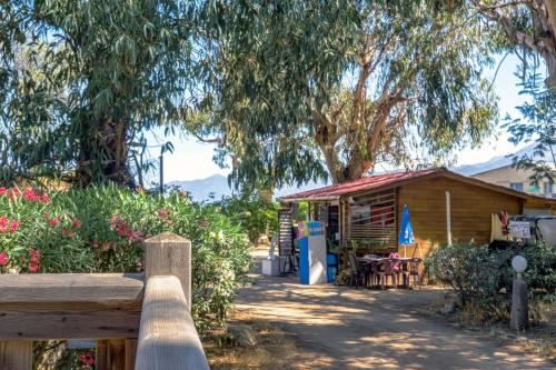 a wooden fence in front of a building with trees at Camping U Pezzo - Mobil home 4 pièces 6/8 personnes Climatisé MAE-2285 in Saint-Florent