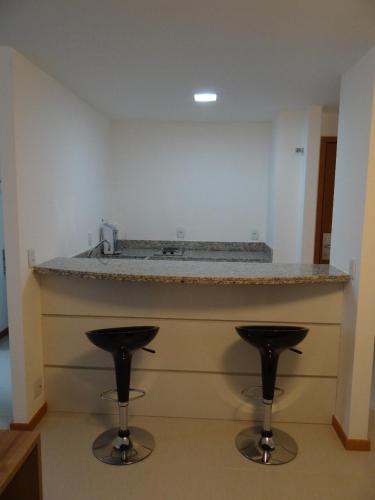 a kitchen with two bar stools under a counter at Residence Flat Prime Itaboraí in Itaboraí