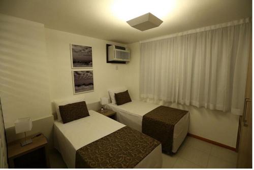 a hotel room with two beds and a window at Residence Flat Prime Itaboraí in Itaboraí