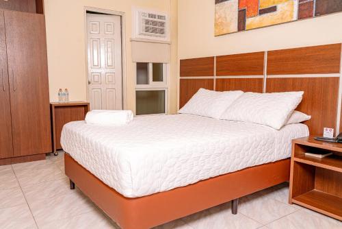 a bedroom with a bed with a wooden headboard at Hotel Benidorm Panama in Panama City