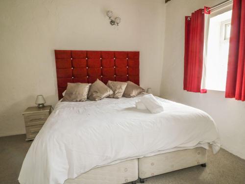a bedroom with a large white bed with a red headboard at Cottage 3 in Keswick