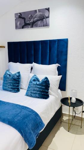 a bed with blue and white pillows and a table at Fourways Luxury Residence in Four Ways