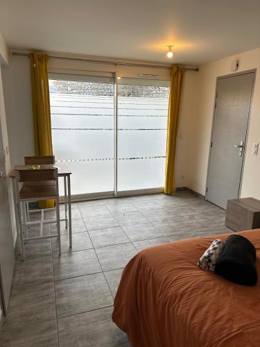a bedroom with a bed and a desk and a window at BOUTON D'OR Studio Terrasse Grand Lit Coin Repas in Château-Arnoux-Saint-Auban
