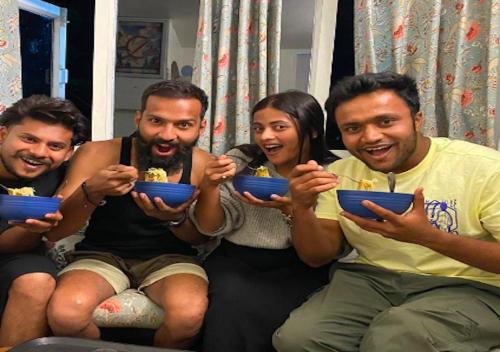 a group of people sitting on a couch eating food at help hostel in Mussoorie