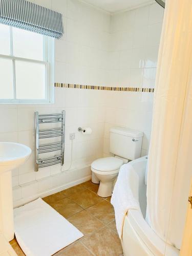 a white bathroom with a toilet and a sink at Beachfront Retreat in Falmouth