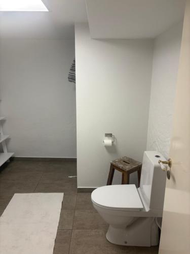 a white bathroom with a toilet and a stool at Herregårdslejlighed in Vrå