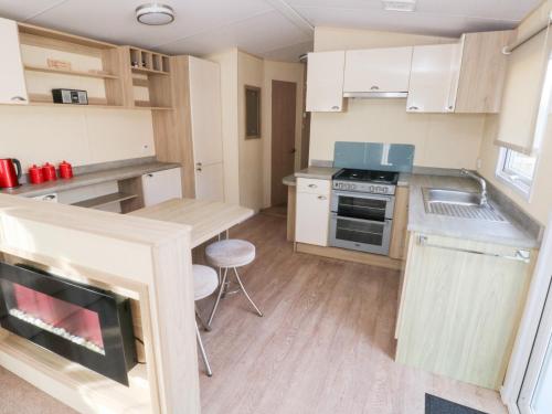 a small kitchen with a stove and a table at Under Cliff Caravan in Ferryside