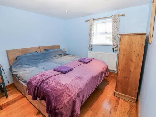 a bedroom with a bed with a purple blanket at Swallows Rest in Hexham