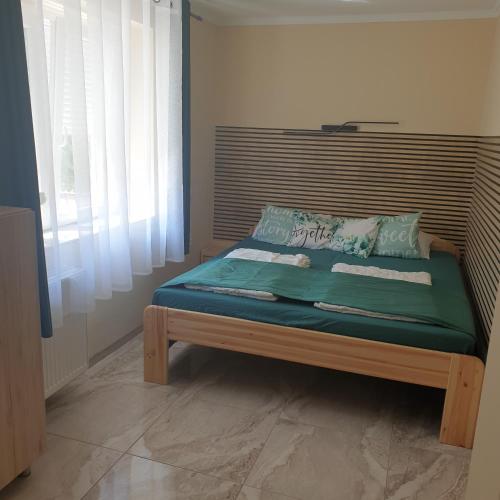 a bed with a wooden headboard in a room at Szabó Vendégház in Bükkszék