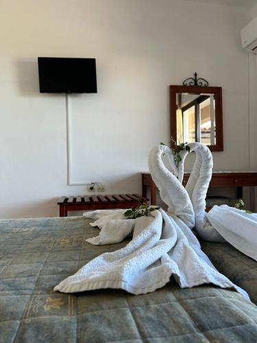 a bed with two swan towels on it at Areti Aparthotel in Áptera