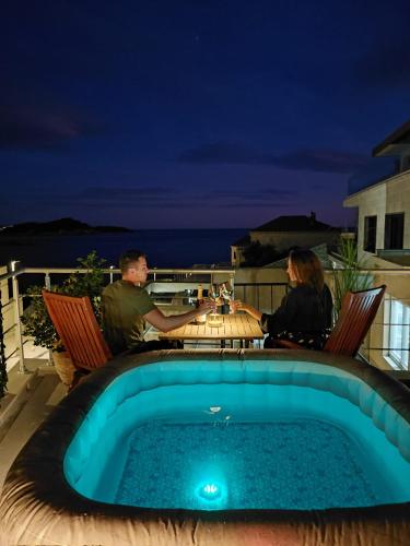 a man and woman sitting at a table next to a pool at Apartment & Room Lady O in Dubrovnik