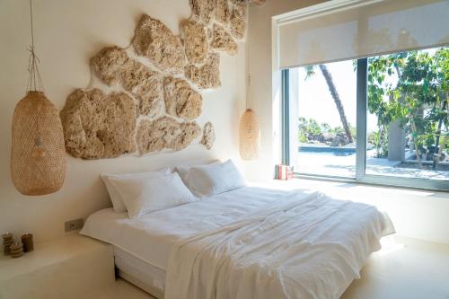 a bedroom with a white bed with a stone wall at Casa Arim in Orosei