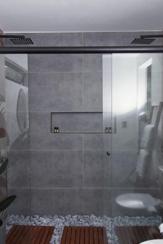 a shower with a glass door with a sink at Chalé Elemental in Morretes
