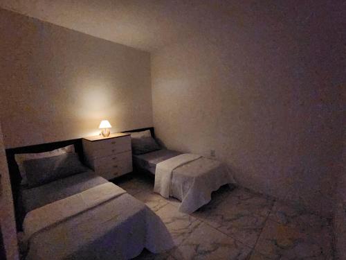 a room with two beds and a dresser with a lamp at Lar de verão casa 01 in Barra de São Miguel