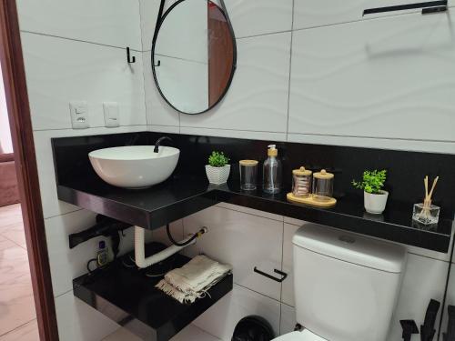 a bathroom with a sink and a mirror and a toilet at Lar de verão casa 01 in Barra de São Miguel