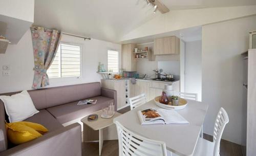 a living room with a couch and a table and a kitchen at Camping U Pezzo - Mobil home 4 pièces 6/8 personnes Climatisé MAE-2285 in Saint-Florent