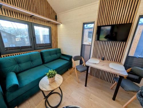a living room with a green couch and a table at Tiny House WaldSEEle in Stuer