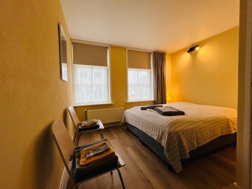 a bedroom with a bed and a table and windows at It Winkelhûs in Terschelling