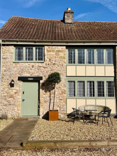 a stone house with a table and a bench in front of it at The Potting Shed at Mathern Palace in Chepstow