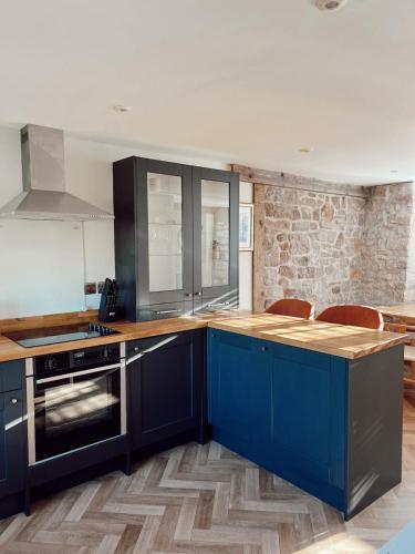 a kitchen with blue cabinets and a wooden counter top at The Potting Shed at Mathern Palace in Chepstow