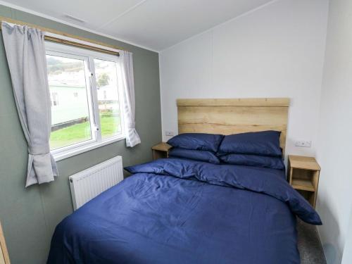 a bedroom with a bed with blue sheets and a window at The Foxy Cobbler in Kingsbridge