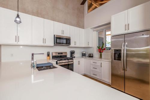 a kitchen with white cabinets and a stainless steel refrigerator at Blue Roatan Resort in West Bay