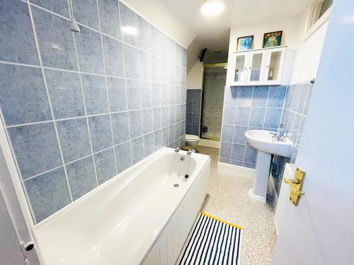 a bathroom with a bath tub and a sink at Langdale Loft - Whitby in Whitby