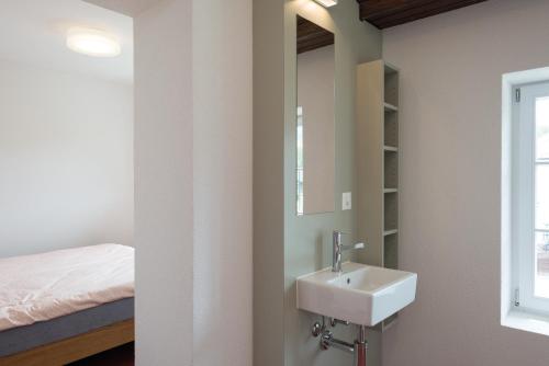 a bathroom with a sink and a mirror and a bed at Avenches Youth Hostel in Avenches
