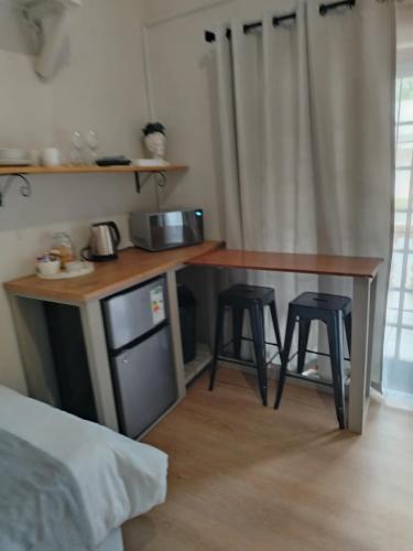 a kitchen with a counter with two stools and a table at KarooRus in Burgersdorp