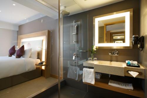 a bathroom with a bed and a shower and a sink at Novotel Yangon Max in Yangon