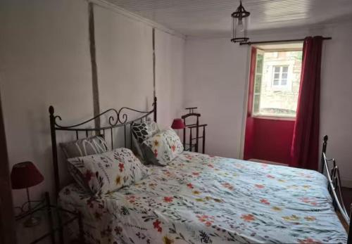 a bedroom with a bed with a floral bedspread and a window at Gîte Pierre, Beynat, Corrèze in Beynat