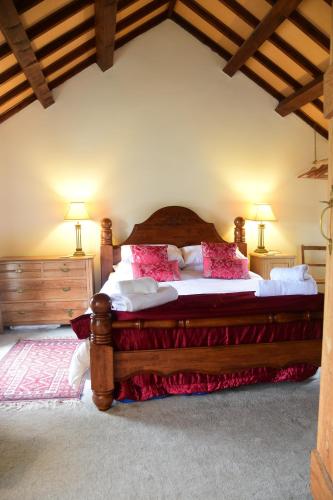 a bedroom with a large wooden bed with pink pillows at Hen Gamdda Fawr in Llanallgo