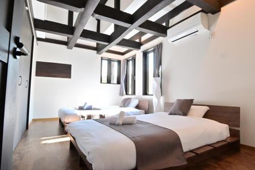 a bedroom with two beds and a ceiling with beams at 愛敬家 in Mobara