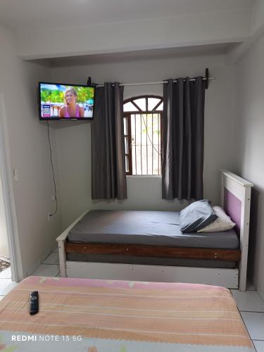 a bedroom with a bed with a tv on the wall at LAR DE PRAIA - Suíte in Serra