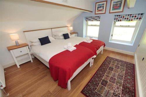 a bedroom with a large bed with a red blanket at 4 Bed in Gower oc-hh471 in Llanmadoc
