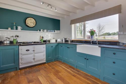 a kitchen with blue cabinets and a clock on the wall at 4 Bed in St. Wenn oc-p00886 in Saint Wenn