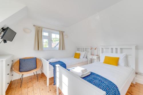 a white bedroom with two beds and a chair at 2 Bed in Sweffling oc-whcs in Rendham