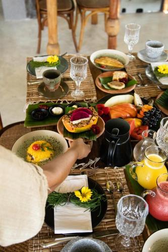 ein Tisch mit Tellern voller Essen und eine Person, die Essen zubereitet in der Unterkunft Zai Patacho in Pôrto de Pedras