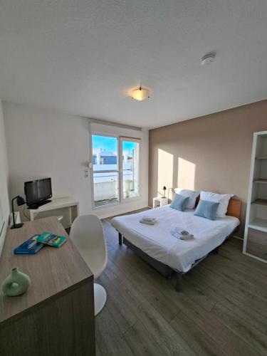 a bedroom with a bed and a desk and a television at Séjours & Affaires La Rochelle Les Minimes in La Rochelle