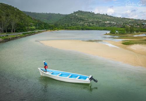 Un hombre parado en un bote en el agua junto a una playa. en Entre Vallee, en Port Mathurin